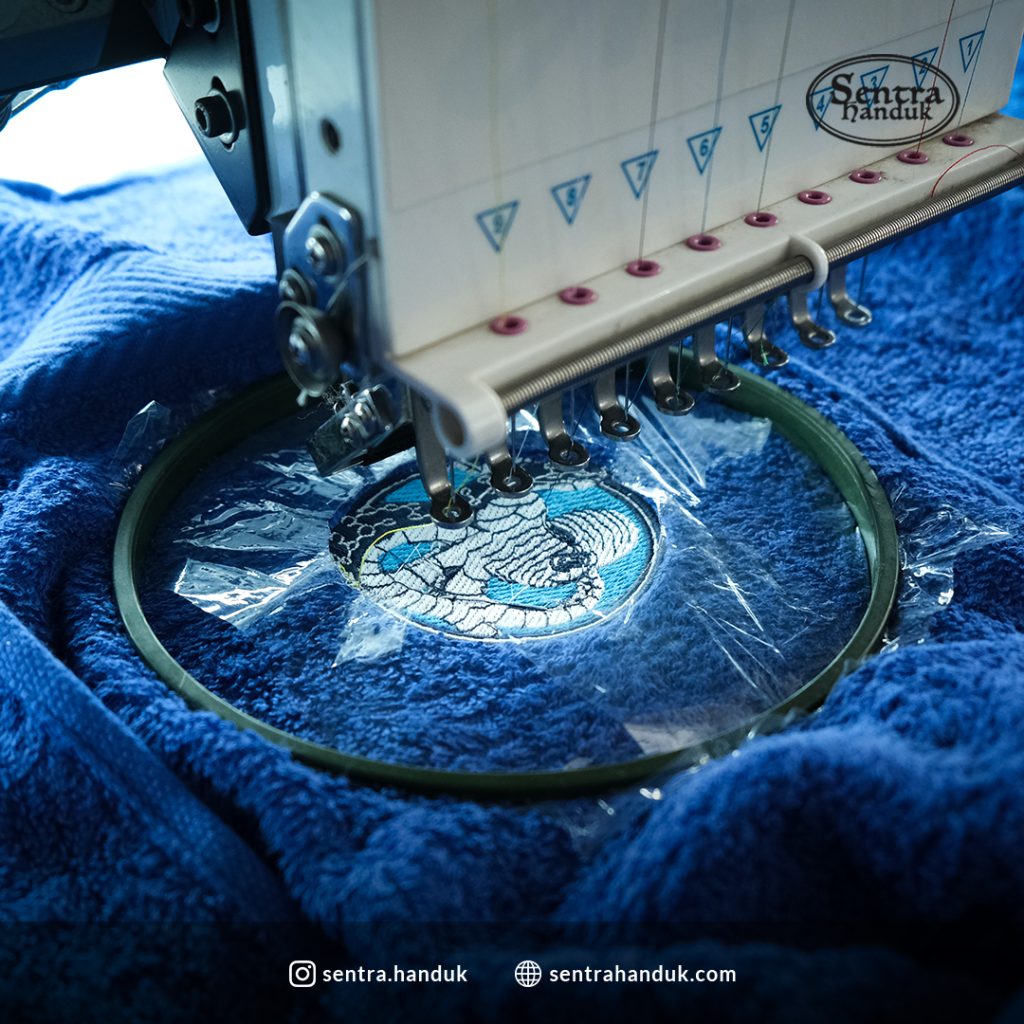 Proses bordir logo pada kain seragam menggunakan mesin bordir modern oleh penyedia jasa pembuatan baju seragam di Indonesia